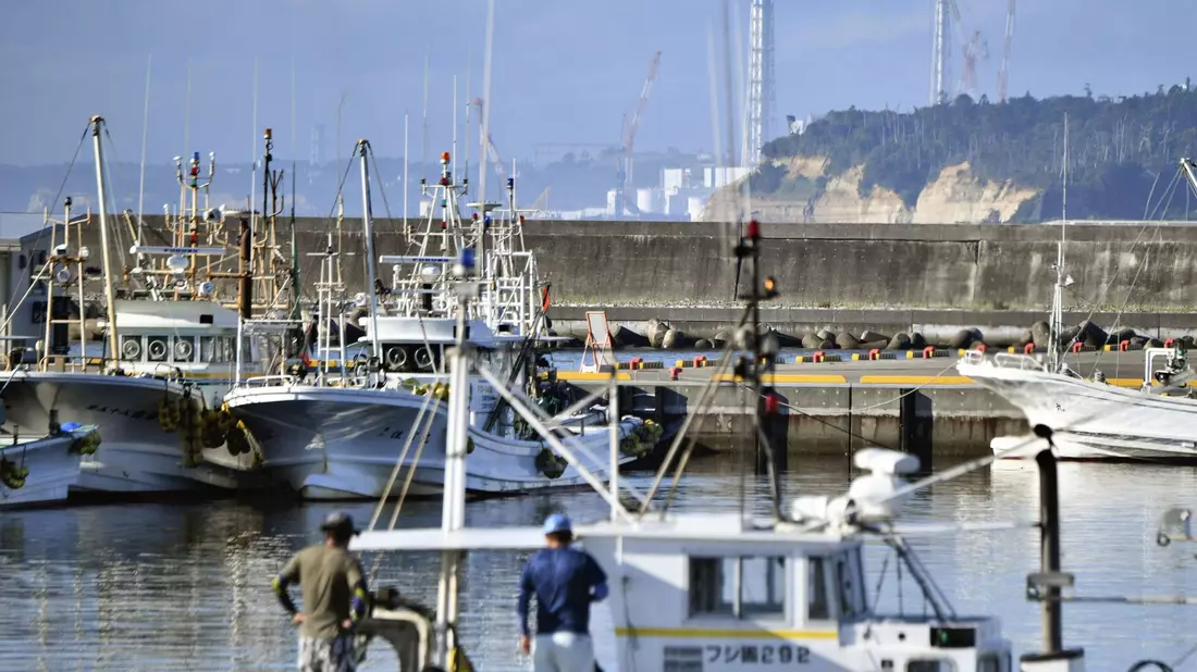 Fischerboote im Hafen von Namie vor dem Hintergrund des havarierten Kernkraftwerks Fukushima Daiichi. - Bild: Uncredited/kyodo/dpa