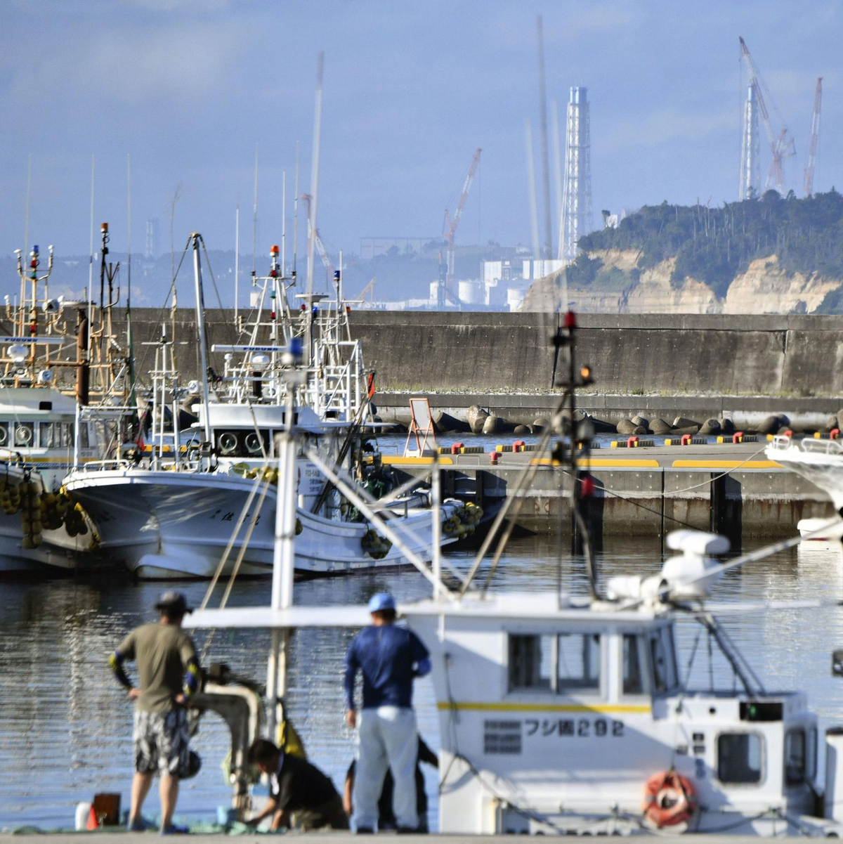 Fischerboote im Hafen von Namie vor dem Hintergrund des havarierten Kernkraftwerks Fukushima Daiichi. - Foto: Uncredited/kyodo/dpa
