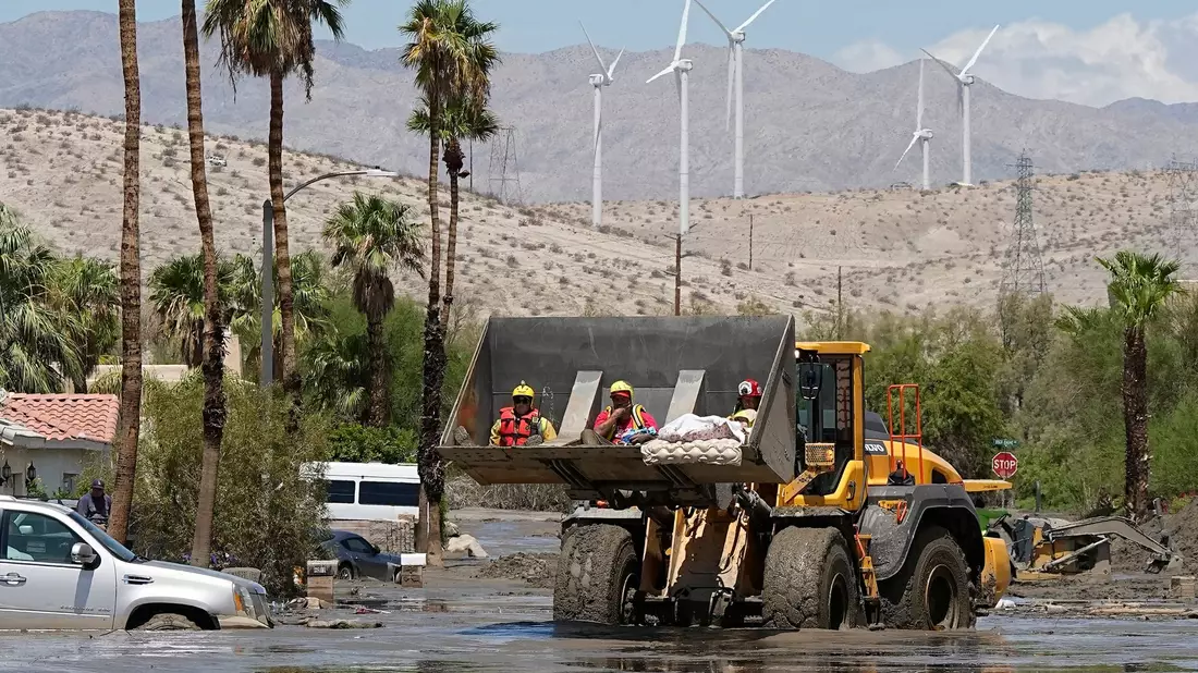 Feuerwehrleute in Cathedral City setzen einen Bagger ein, um eine Person aus einem Zentrum für betreutes Wohnen zu retten, nachdem die Straße mit Schlamm überflutet wurde. - Bild: Mark J. Terrill/AP/dpa