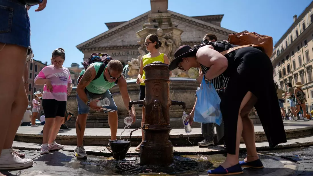 Menschen kühlen sich an einem Springbrunnen vor dem Pantheon in Rom ab. - Bild: Andrew Medichini/AP/dpa