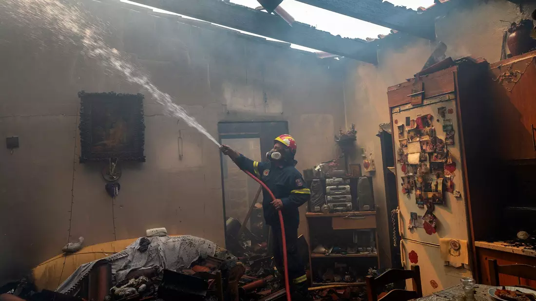 Bewohner und Feuerwehrleute bekämpfen die Flammen. - Bild: Marios Lolos/XinHua/dpa