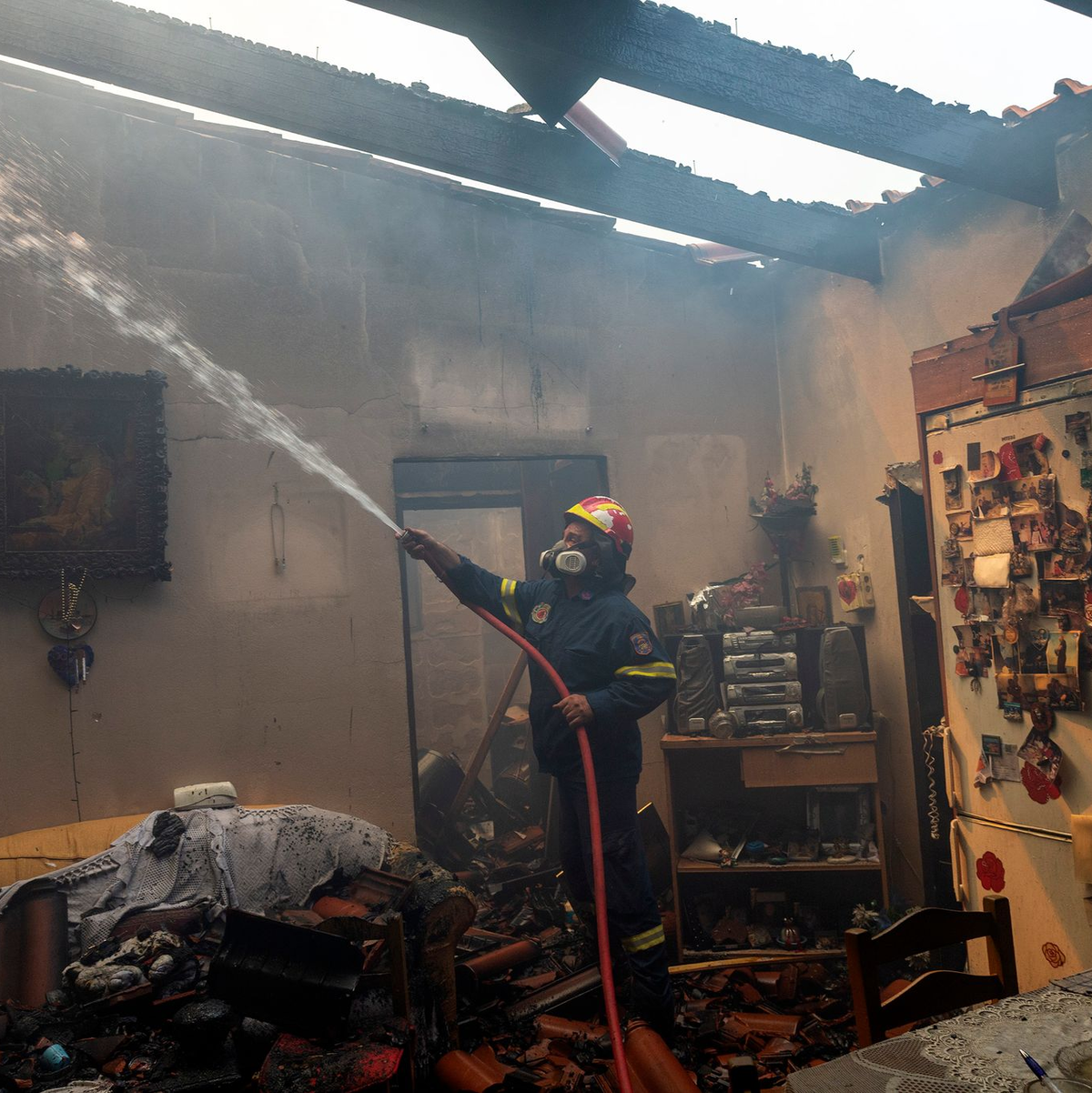 Ein Feuerwehrmann löscht ein Haus im Dorf Hasia in der Nähe von Athen. - Foto: Marios Lolos/XinHua/dpa