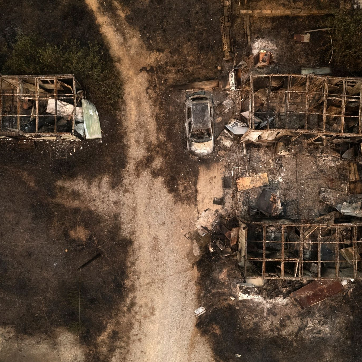 Ein verbranntes Auto und ausgebrannte Lagerhäuser in Palagia. - Foto: Achilleas Chiras/AP/dpa