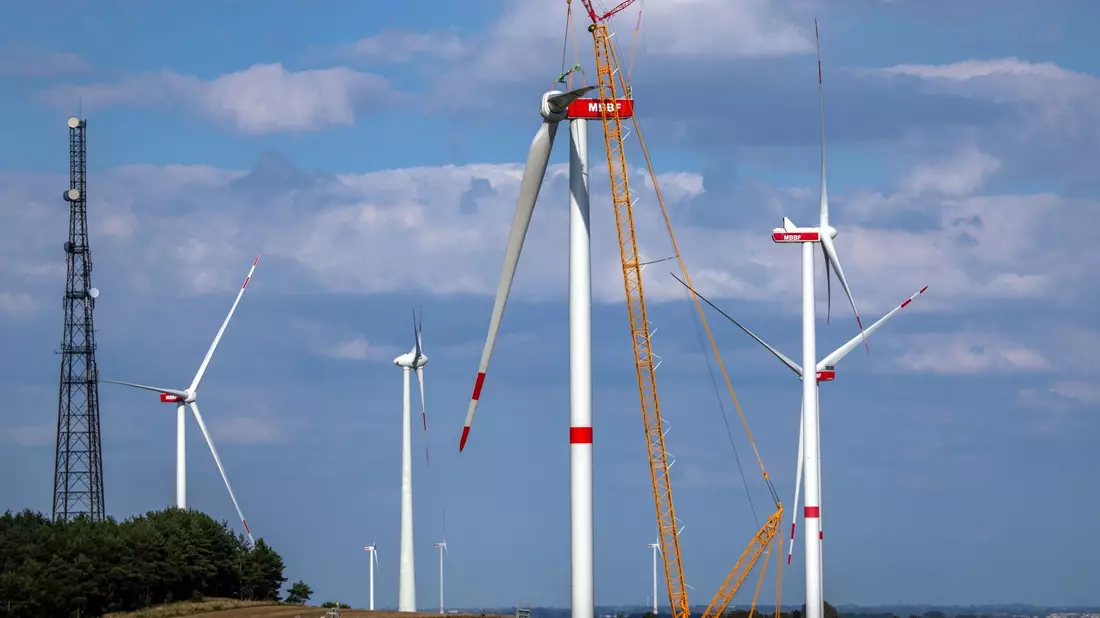 Ein Kran hebt auf der Baustelle eines neuen Windparks in Mecklenburg-Vorpommern ein Rotorblatt für die Montage an das Generatorhaus. - Bild: Jens Büttner/dpa