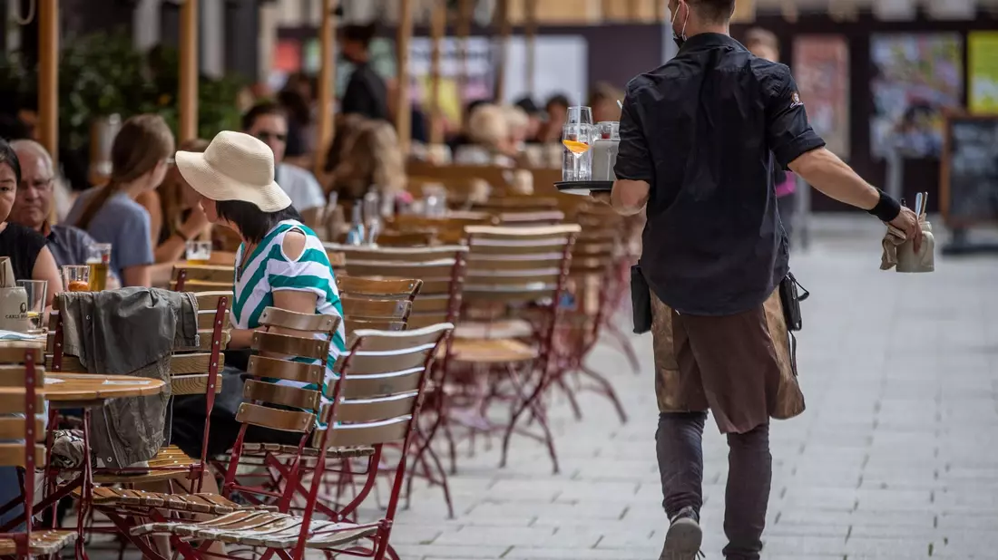 Eine Servicekraft bedient im Außenbereich eines Restaurants die Gäste. - Bild: Christoph Schmidt/dpa