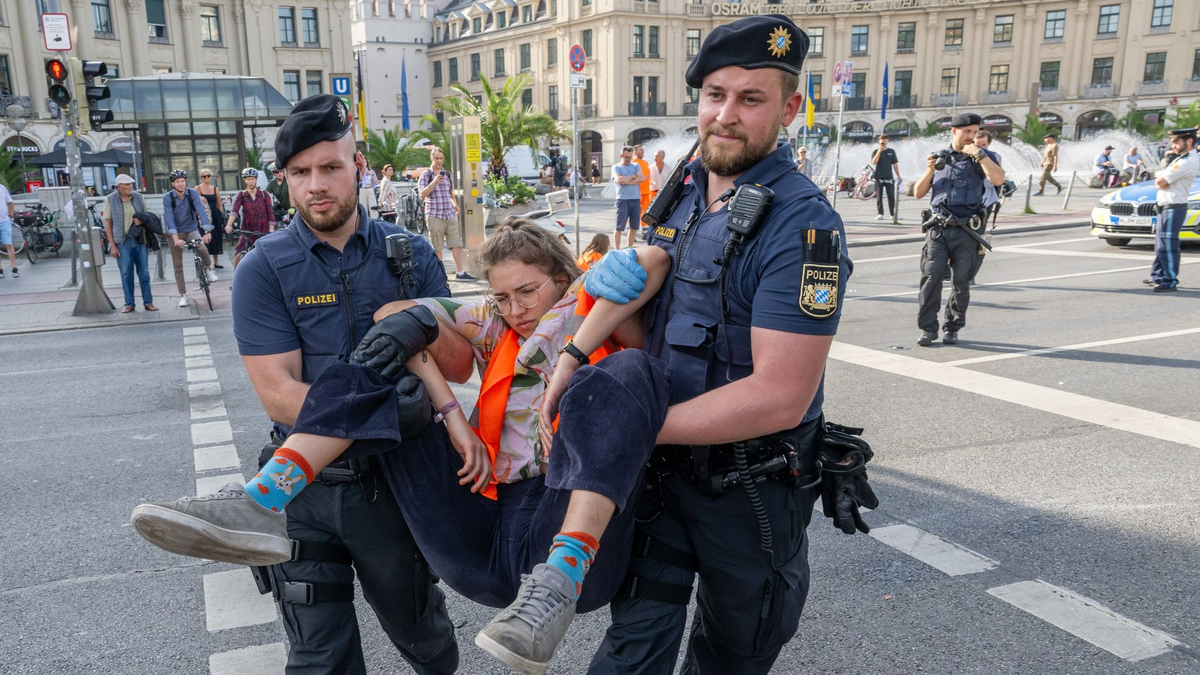Polizisten tragen auf der Kreuzung am Stachus in der Münchener Innenstadt Aktivisten der Letzten Generation weg. Ihre Aktionen werden teilweise verboten. - Foto: Peter Kneffel/dpa