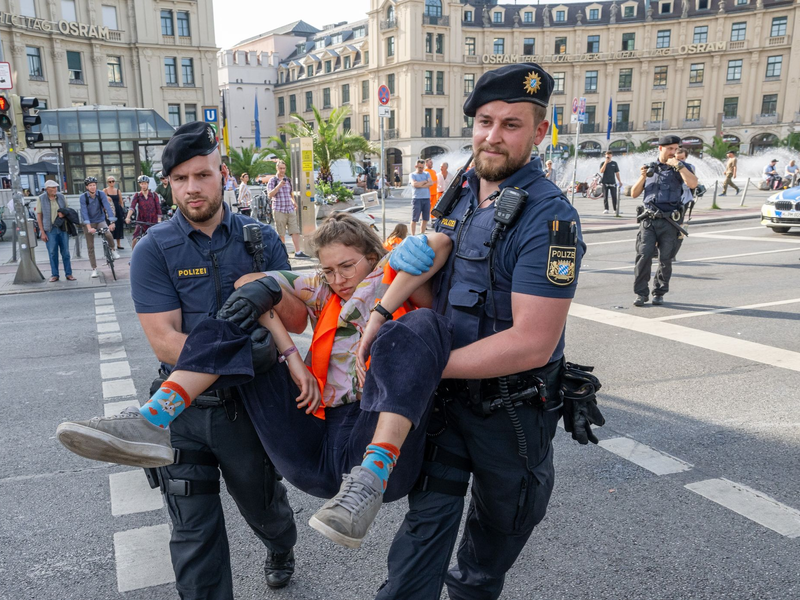 Polizisten tragen auf der Kreuzung am Stachus in der Münchener Innenstadt Aktivisten der Letzten Generation weg. Ihre Aktionen werden teilweise verboten. - Foto: Peter Kneffel/dpa
