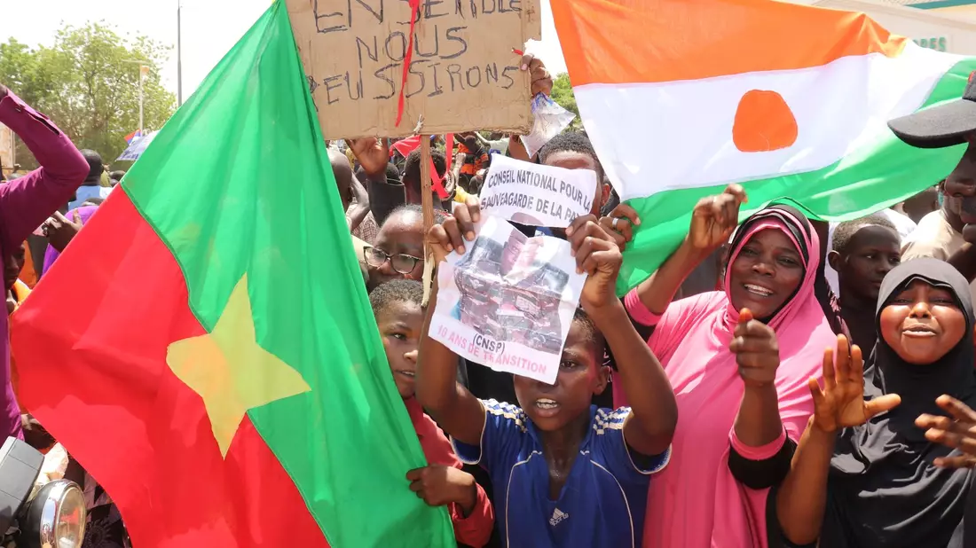 Befürworter des Putschs halten eine Flagge von Burkina Faso (l) und Niger hoch. Die beiden Länder haben einen Pakt geschlossen. - Bild: Djibo Issifou/dpa
