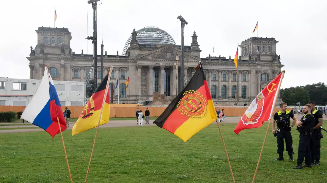 Jahrestag der Erstürmung des Reichstagsgebäudes: Fahnen stehen heute bei einer rechtsextremen Kundgebung vor dem Reichstagsgebäude. - Bild: Paul Zinken/dpa