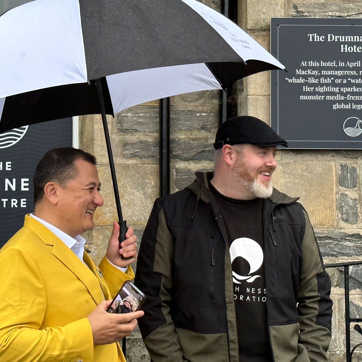 Paul Nixon (l) vom Loch Ness Centre und der Projektleiter Alan McKenna neben der Plakette, die an eine berühmte Nessie-Sichtung im Jahr 1933 erinnert. - Foto: Benedikt von Imhoff/dpa