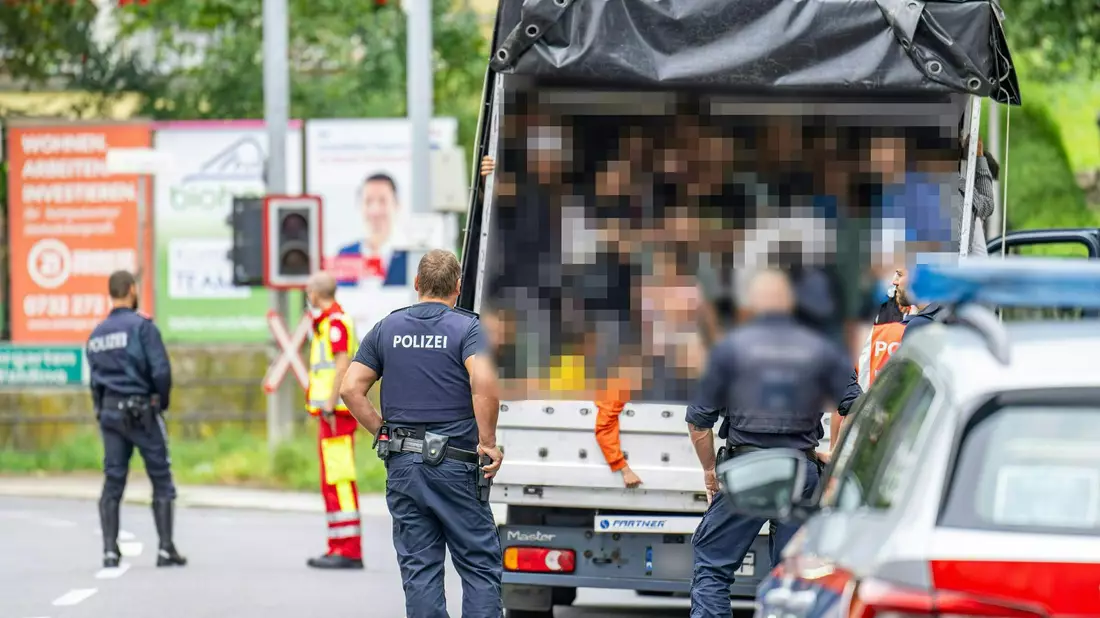 Polizisten stehen bei einer Kontrolle in Österreich an einem Kleintransporter. Die Beamten entdeckten dabei 53 Personen auf der Ladefläche. - Bild: Werner Kerschbaummayr/Fotokersch/APA/dpa