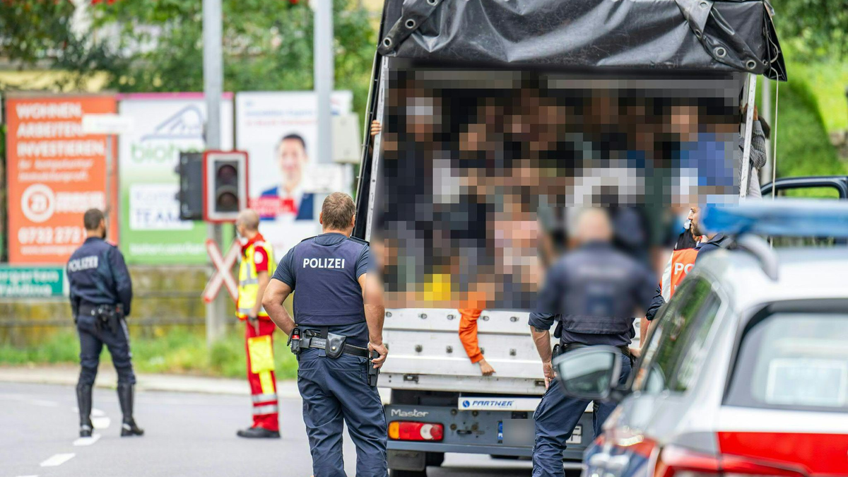 Polizisten stehen bei einer Kontrolle in Österreich an einem Kleintransporter. Die Beamten entdeckten dabei 53 Personen auf der Ladefläche. - Foto: Werner Kerschbaummayr/Fotokersch/APA/dpa