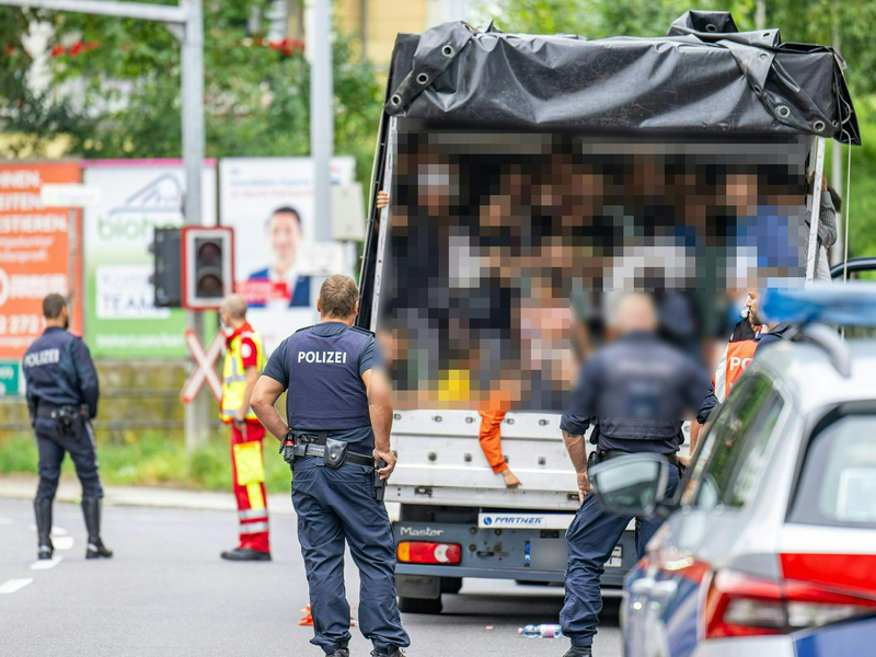 Polizisten stehen bei einer Kontrolle in Österreich an einem Kleintransporter. Die Beamten entdeckten dabei 53 Personen auf der Ladefläche. - Foto: Werner Kerschbaummayr/Fotokersch/APA/dpa