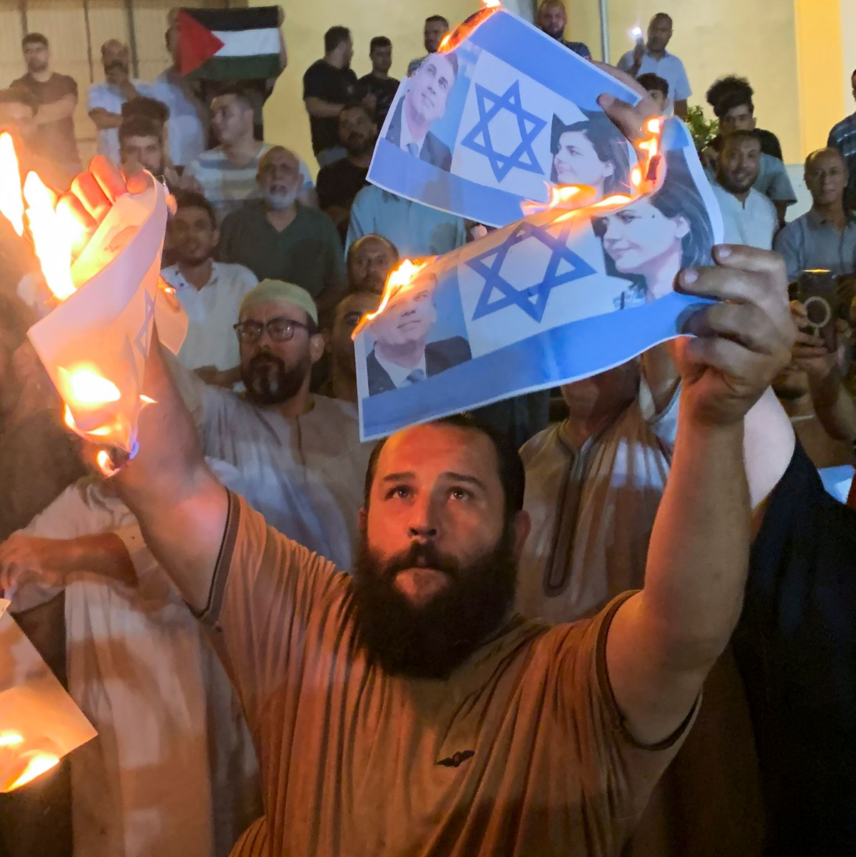 Menschen verbrennen Fotos, die den israelischen Außenminister Eli Cohen und seine libysche Amtskollegin Nadschla al-Mankusch zeigen. In Libyen ist es in der Nacht zum Montag zu gewaltsamen Protesten gekommen. - Foto: Yousef Murad/AP