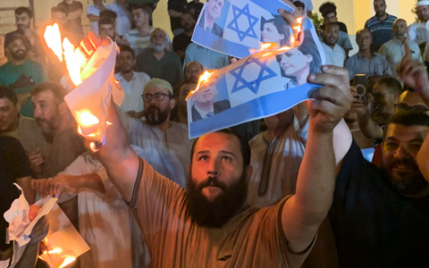 Menschen verbrennen Fotos, die den israelischen Außenminister Eli Cohen und seine libysche Amtskollegin Nadschla al-Mankusch zeigen. In Libyen ist es in der Nacht zum Montag zu gewaltsamen Protesten gekommen. - Foto: Yousef Murad/AP