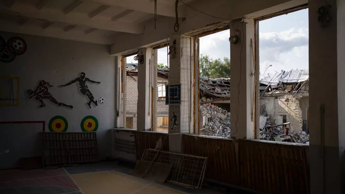 In Kupjansk ist durch die zerbrochenen Fenster einer Turnhalle die zerstörte Bibliothek einer Schule zu sehen. - Bild: Bram Janssen/AP