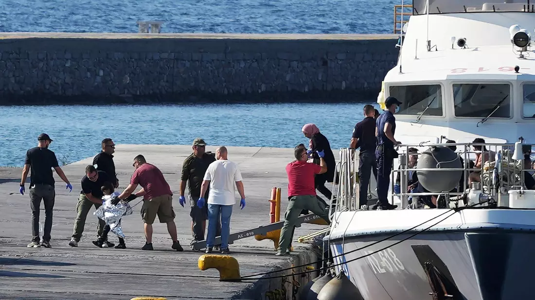 Menschen werden nach der Rettungsaktion im Hafen von Mytilini auf Lesbos von Beamten der Küstenwache eskortiert. - Bild: Panagiotis Balaskas/AP/dpa