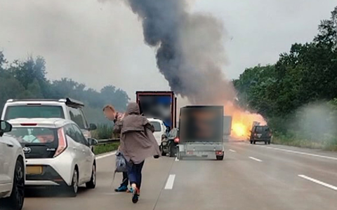 Autofahrer verlassen ihre Fahrzeuge, während im Hintergrund ein Lkw in Flammen steht. Nach einem Auffahrunfall sind auf einem Gefahrguttransporter mehrere Gasflaschen explodiert. - Foto: -/TNN/dpa Autofahrer verlassen ihre Fahrzeuge, während im Hintergrund ein Lkw in Flammen steht. Nach einem Auffahrunfall sind auf einem Gefahrguttransporter mehrere Gasflaschen explodiert. - Foto: -/TNN/dpa