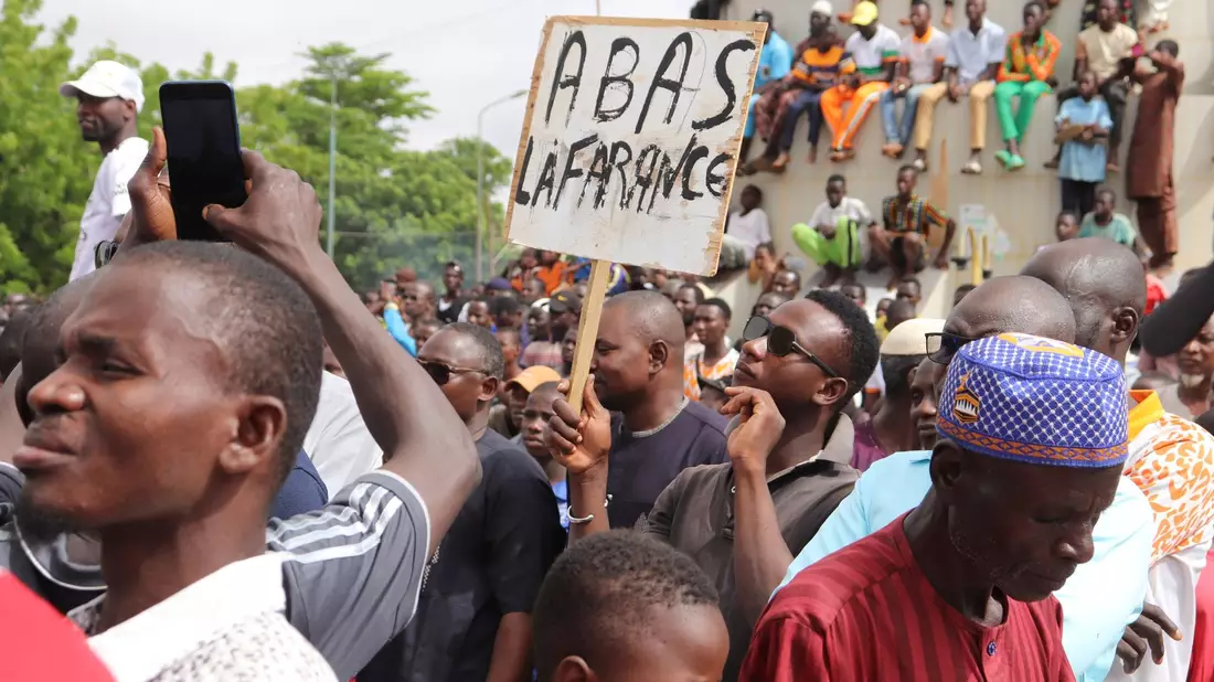 Menschen demonstrieren am 03.08.2023 in Nigers Hauptstadt Niamey, um damit ihre Unterstützung für die Putschisten zu zeigen. Ein junger Mann hält dabei ein Schild mit der Aufschrift «A bas la France» (Nieder mit Frankreich) in die Höhe. - Bild: 1