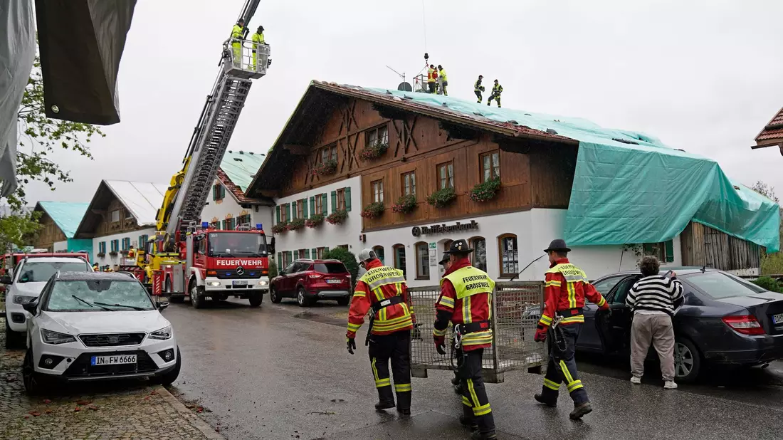 Arbeiter und Feuerwehrleute beseitigen die Unwetter-Schäden im oberbayerischen Bad Bayersoien. Bei dem Unwetter wurden viele Dächer beschädigt. - Bild: Uwe Lein/dpa