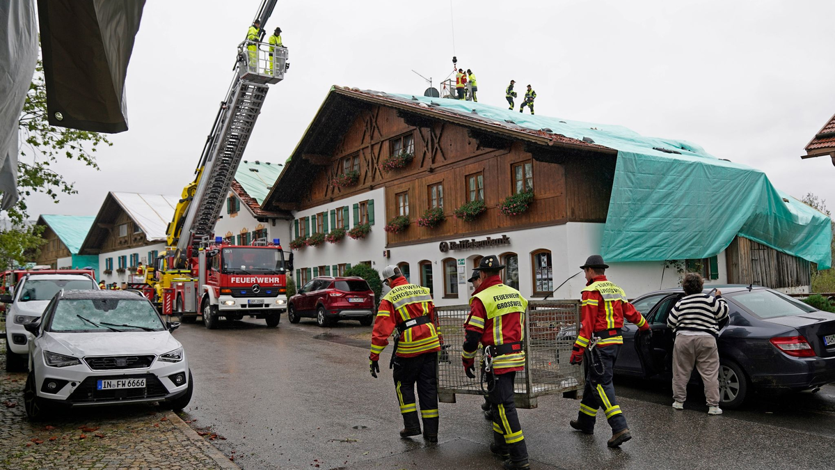 Arbeiter und Feuerwehrleute beseitigen die Unwetter-Schäden im oberbayerischen Bad Bayersoien. Bei dem Unwetter wurden viele Dächer beschädigt. - Foto: Uwe Lein/dpa