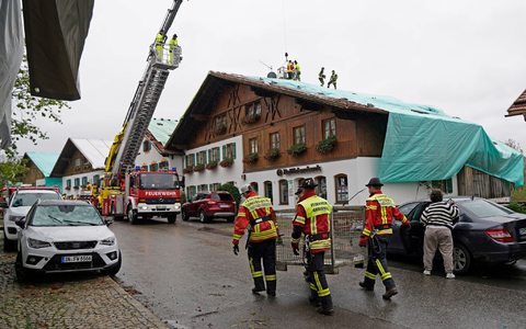Arbeiter und Feuerwehrleute beseitigen die Unwetter-Schäden im oberbayerischen Bad Bayersoien. Bei dem Unwetter wurden viele Dächer beschädigt. - Foto: Uwe Lein/dpa