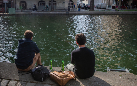 Zwei junge Männer trinken am Ufer des Kanals Saint-Martin in Paris gemeinsam Bier. - Foto: Aurelien Morissard/XinHua/dpa