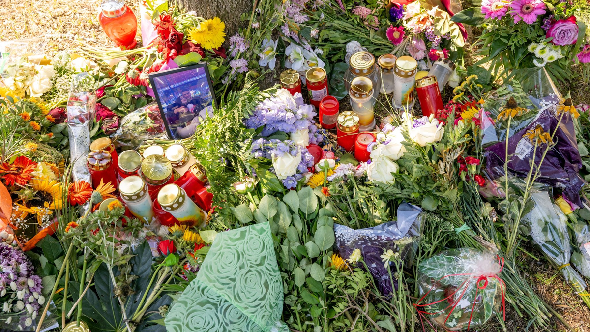 Blumen, Kerzen und Bilder liegen an einem Baum, in dessen Nähe am 17. August 2022 die tote Frau in einem Auto entdeckt wurde. - Foto: Peter Kneffel/dpa/Archiv