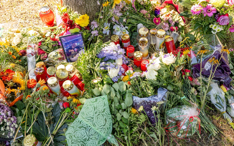 Blumen, Kerzen und Bilder liegen an einem Baum, in dessen Nähe am 17. August 2022 die tote Frau in einem Auto entdeckt wurde. - Foto: Peter Kneffel/dpa/Archiv