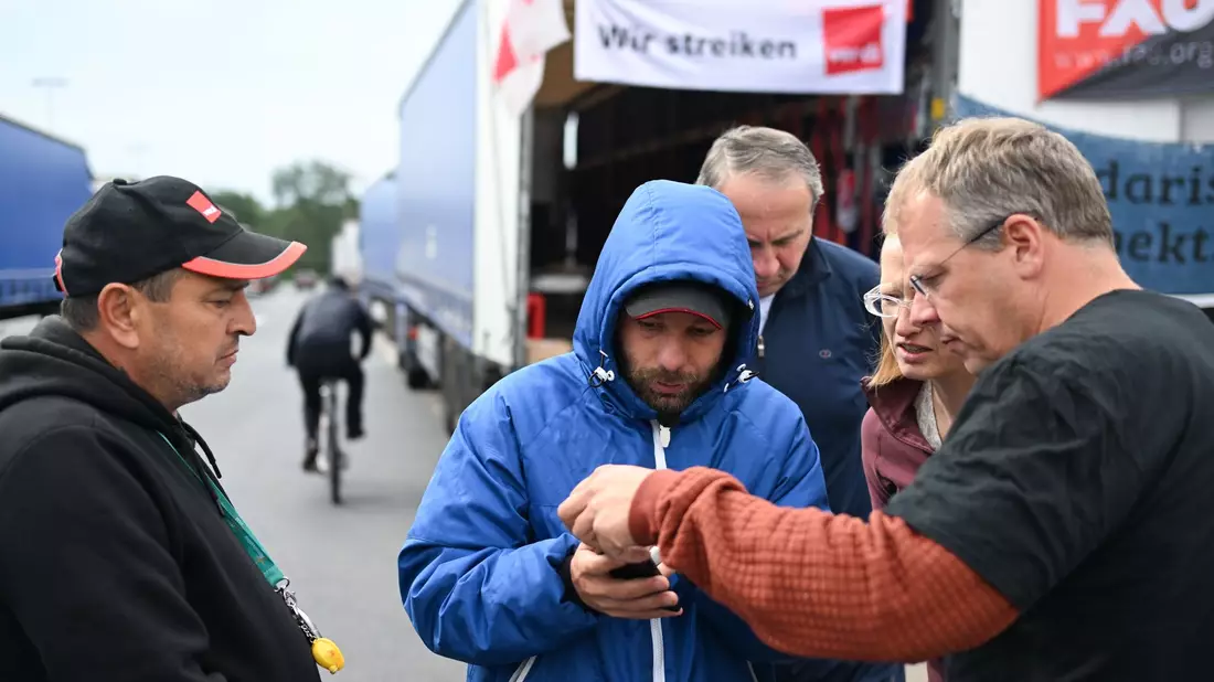 Der niederländische Gewerkschafter Edwin Atema (r) spricht mit den Lkw-Fahrern. - Bild: Arne Dedert/dpa