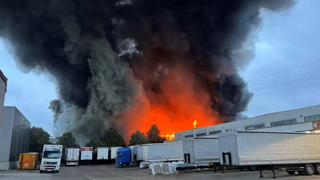 Das Feuer in einer Lagerhalle sorgte für eine hohe Rauchwolke über dem Bezirk Marzahn-Hellersdorf. - Bild: Dominik Totaro/dpa