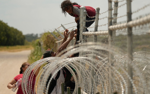 Migranten, die den Rio Grande von Mexiko in die USA überquert haben, klettern in Texas über einen Zaun mit Stacheldraht. - Foto: Eric Gay/AP