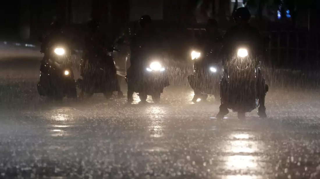 Rollerfahrer stehen bei heftigem Regen an einer Kreuzung in Taipeh. - Bild: Chiang Ying-ying/AP