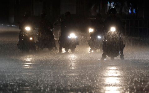 Rollerfahrer stehen bei heftigem Regen an einer Kreuzung in Taipeh. - Foto: Chiang Ying-ying/AP