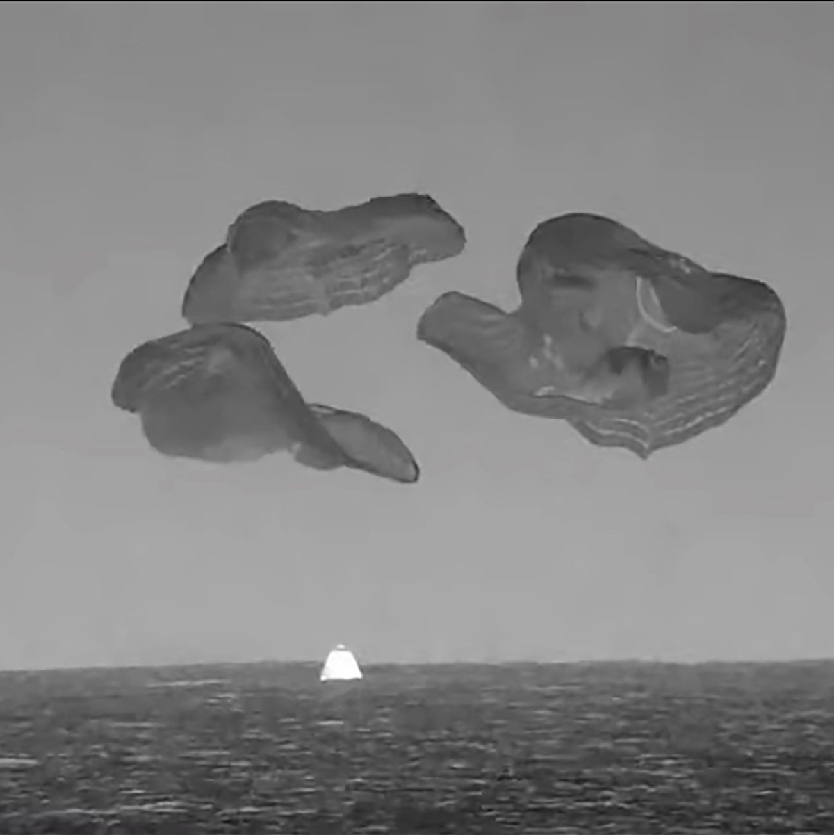 In diesem Bild aus einem von der NASA zur Verfügung gestellten Video taucht eine SpaceX-Kapsel, die von Fallschirmen gebremst wird,in den Atlantik vor der Küste Floridas ein. - Foto: NASA via AP