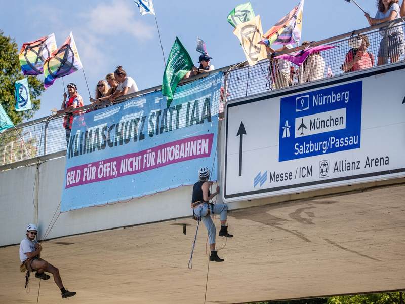Klimaaktivisten von Extinction Rebellion seilen sich in München von einer Brücke ab. - Foto: Christoph Schmidt/dpa