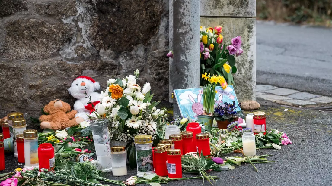 An einer Mauer vor dem Kinder- und Jugendhilfezentrum in Wunsiedel liegen Blumen, Kuscheltiere und Kerzen. - Bild: Daniel Vogl/dpa