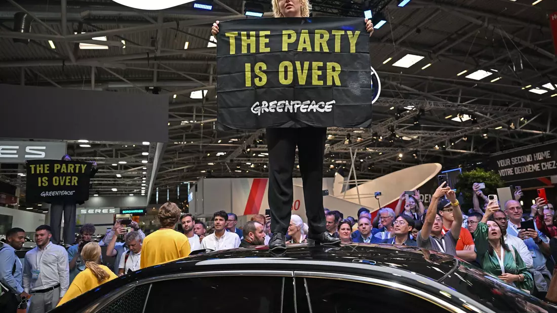 Eine Greenpeace-Aktivistin bei der Eröffnung der IAA auf dem Dach eines ausgestellten Autos. - Bild: Sven Hoppe/dpa