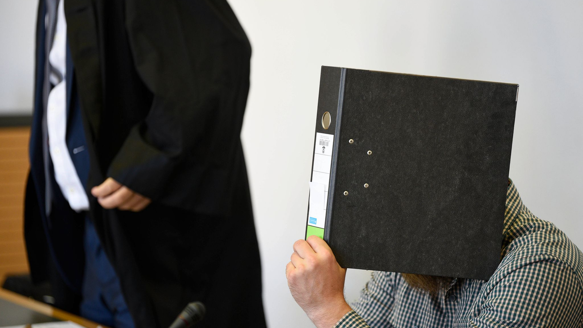 Der Angeklagte verbirgt sein Gesicht vor Gericht hinter einem Aktenordner. - Foto: Frank Hormann/dpa