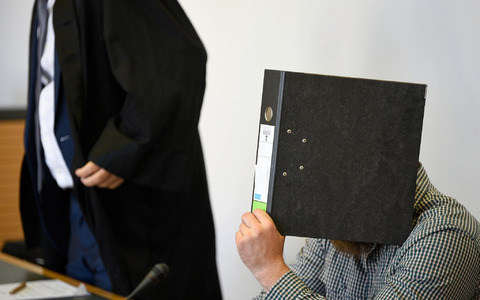 Der Angeklagte verbirgt sein Gesicht vor Gericht hinter einem Aktenordner. - Foto: Frank Hormann/dpa