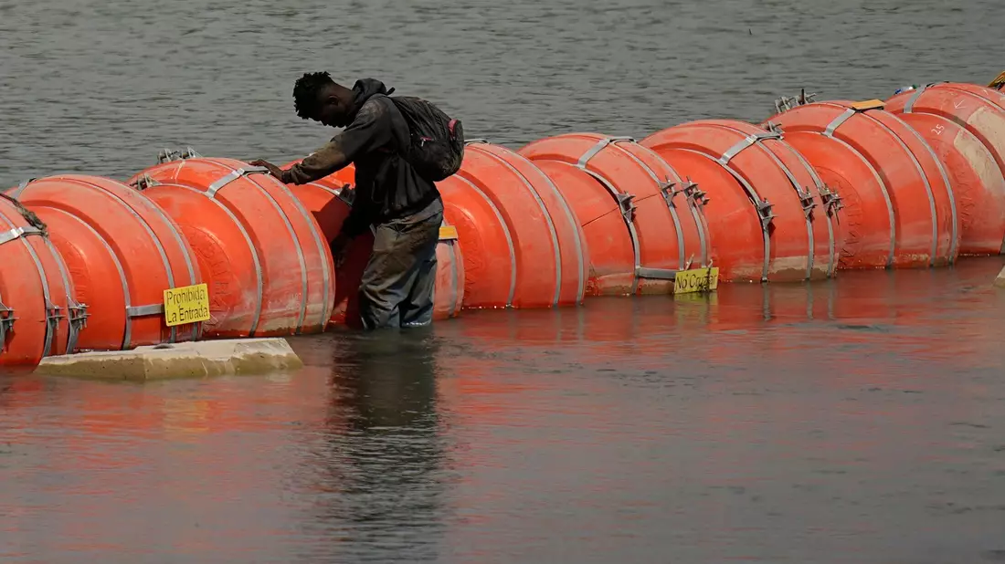 Ein Migrant aus Kolumbien steht an einer schwimmenden Bojenbarriere, um den Rio Grande von Mexiko in die USA zu überqueren. - Bild: Eric Gay/AP/dpa