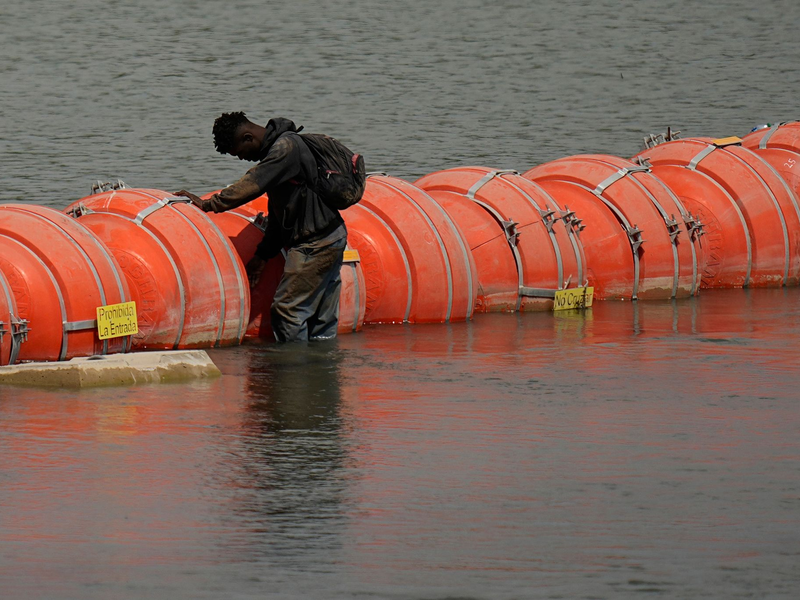 Ein Migrant aus Kolumbien steht an einer schwimmenden Bojenbarriere, um den Rio Grande von Mexiko in die USA zu überqueren. - Foto: Eric Gay/AP/dpa