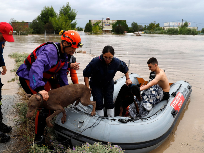 Feuerwehrleute mit einem Schlauchboot evakuieren Menschen und ihre Hunde aus überfluteten Gebäuden. - Foto: Vaggelis Kousioras/AP/dpa