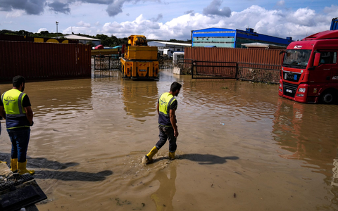 Arbeiter laufen nach Überschwemmungen durch schwere Regenfälle durch das Hochwasser. - Foto: Khalil Hamra/AP/dpa