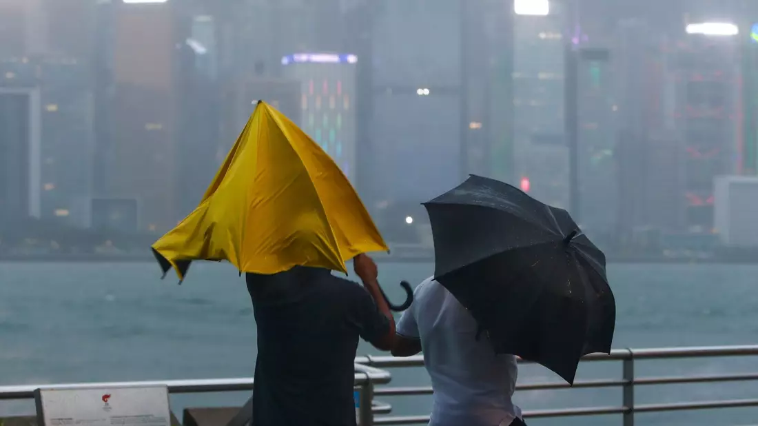 Menschen mit Regenschirmen kämpfen in Hongkong mit starkem Wind und Regen des Taifuns «Saola». - Bild: Daniel Ceng/AP/dpa