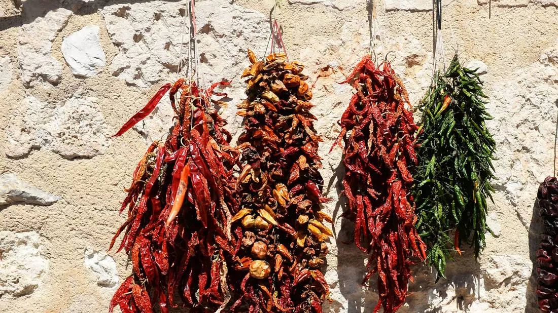 Getrocknete Paprikas und Chillis hängen auf einem Markt zum Verkauf. - Bild: Jens Kalaene/dpa-Zentralbild/dpa
