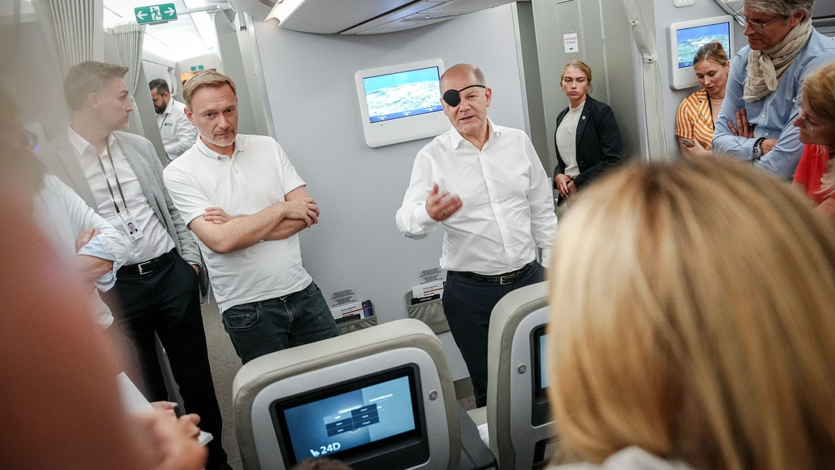 Bundeskanzler Olaf Scholz (r, SPD) und Finanzminister Christian Lindner (FDP) sprechen auf dem Flug nach Neu Dehli mit Journalisten. - Foto: Kay Nietfeld/dpa