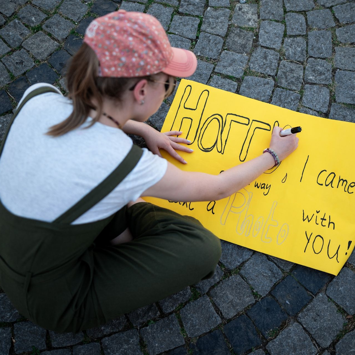 Eine junge Frau schreibt auf ein Schild: «Harry, I came all the way to take a photo with you!» - Foto: Fabian Strauch/dpa