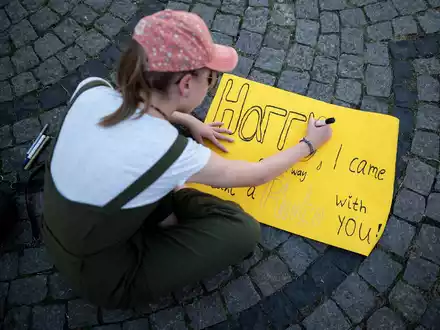 Eine junge Frau schreibt auf ein Schild: «Harry, I came all the way to take a photo with you!» - Foto: Fabian Strauch/dpa