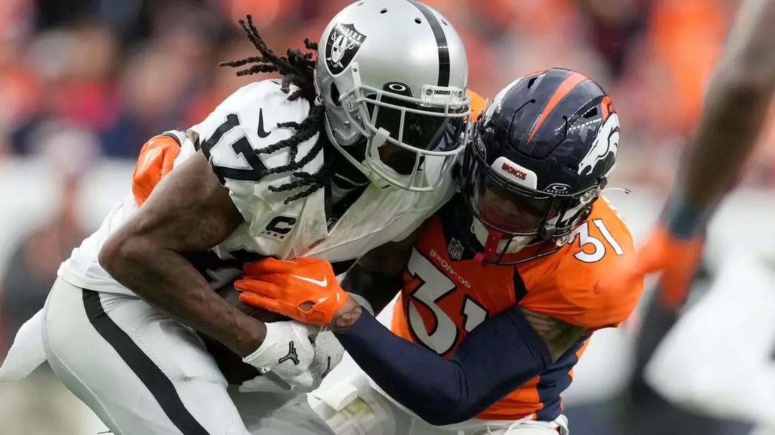 Davante Adams (17), Wide Receiver der Las Vegas Raiders, wird in der zweiten Hälfte von Justin Simmons (31), Safety der Denver Broncos, angegriffen. - Bild: David Zalubowski/AP/dpa